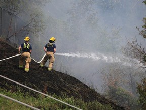 Calgary firefighters deal with a large grass fire on McHugh Bluff below Crescent Heights that burned into the backyards of homes along the ridge on Monday, June 5, 2023.