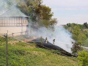 Calgary firefighters deal with a large grass fire on McHugh Bluff below Crescent Heights that burned into the backyards of homes along the ridge on Monday, June 5, 2023.