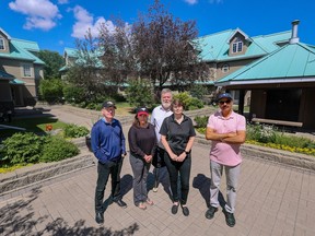 Some of the residents of the River Run Townhouses in Eau Claire pose for a photo in the courtyard of the development on Saturday, June 17, 2023. The residents are objecting to having their homes expropriated by the City of Calgary to make way for the Green Line.