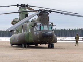 A Royal Canadian Air Force member observes as a CH-147 Chinook prepares to take off April 10, 2021 at Thompson, Man., during Operation VECTOR.