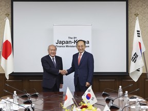 In this photo provided by Japan's Finance Ministry, Japanese Finance Minister Shunichi Suzuki, left, and South Korea's Economy and Finance Minister Choo Kyungho shake hands as they pose for a photo before their meeting at the finance ministry in Tokyo, Thursday, June 29, 2023. Japan and South Korea agreed Thursday to revive a currency swap agreement for times of crisis, in the latest sign of warming ties as the countries work to smooth over historical antagonisms dating back nearly a century. (Japan's Finance Ministry via AP)