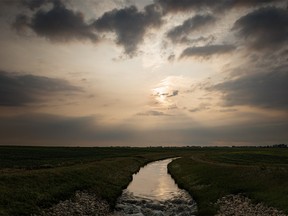 Smoke-tinted sunset over an irrigation canal at Lyalta, Ab., on Wednesday, July 5, 2023.