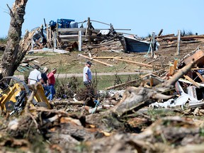 Family members survey damage of their house on Sunday, July 2, 2023, after a tornado destroyed property on Highway 2A between Didsbury and Carstairs the day before.