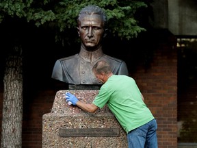 A volunteer scrubs spray paint off the Roman Shukhevych statue at the Ukrainian Youth Unity Complex, 9615 153 Ave., in Edmonton Tuesday Aug. 10, 2021.