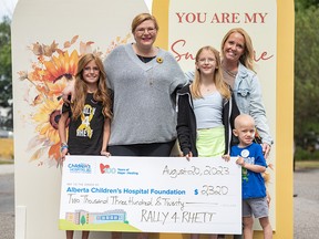Halle Bold, Rhett Johnson’s cousin, left, Heather Roy, Evelyn’s mother, Harper, Evelyn’s sister, Kirstin Johnson, Rhett’s mother, and Rhett Johnson, who is battling cancer, 4, pose for a photo with a cheque during Evelyn Roy’s birthday in a driveway dance party on Sunday, August 20, 2023.