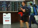 A passenger walks by a sign directing evacuees at the Calgary airport on Thursday, Aug. 17, 2023.