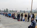 People without vehicles line up to register for a flight to Calgary in Yellowknife on Thursday, August 17, 2023. Communities receiving evacuees from the Northwest Territories fleeing wildfires have sprung into action to lend a helping hand.