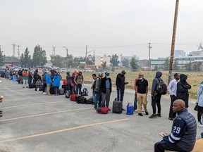 People without vehicles lineup to register for a flight to Calgary in Yellowknife on Thursday, August 17, 2023. Communities receiving evacuees from the Northwest Territories fleeing wildfires have sprung into action to lend a helping hand.