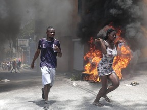 Demonstrators run past tires set on fire during a protest against insecurity in Port-au-Prince, Haiti, Monday, Aug. 7, 2023.