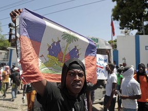 A demonstrator holds up a Haitian flag during a protest against insecurity in Port-au-Prince, Haiti, Monday, Aug. 7, 2023.