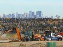 Workers install streetlight facilities in a new neighborhood with the Calgary skyline in the background on Wednesday, Sept. 27.