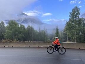 An image of a woman cycling along the Bow Valley Parkway in Banff National Park in Alberta, Canada.