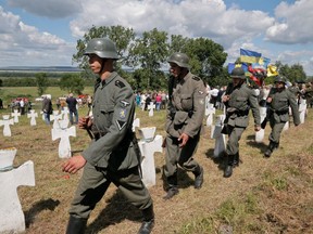 Ukrainians dressed in SS Galicia Division uniforms march past graves during a re-burial ceremony at the SS Galicia Division cemetery near the village of Chervone, Ukraine, in 2013.