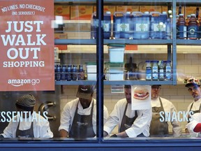 In this Jan. 22, 2018, file photo, workers as seen from a sidewalk window as they assemble sandwiches in an Amazon Go store in Seattle. Toronto and Calgary sports fans will soon be able to skip the lineup when purchasing snacks before or during games. The Scotiabank Arena in Toronto and Scotiabank Saddledome in Calgary are rolling out Amazon technology allowing some of the venue's stores to offer fans checkout-free shopping.