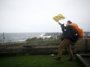 A man tries to hold his umbrella along Dallas Road during a storm in Victoria, Tuesday, Jan. 5, 2021. Forecasters are warning of high winds and heavy rain to hit parts of the British Columbia coastline in the first storm of the fall season.