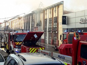 This handout photograph taken and released on October 1, 2023 by the 112 Emergency Services of the Murcia Region shows firefighters spraying the facade of the Teatre nightclub as at least thirteen people were killed in a fire, in Murcia.