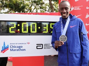 Kelvin Kiptum of Kenya poses with his medal and the clock after setting a world record marathon time of 2:00.35 during the 2023 Chicago Marathon on October 08, 2023 in Chicago, Illinois.