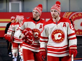 : Elias Lindholm #28 and Jonathan Huberdeau #10 of the Calgary Flames and their teammates make their way to the ice surface before practice at Commonwealth Stadium on October 28, 2023 in Edmonton