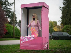 Anne Bruinn stands dressed as a Barbie doll inside a box in an attempt to entertain motorists driving past her home in Vancouver, on Thursday, October 19, 2023.
