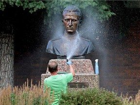 A volunteer washes spray paint off the Roman Shukhevych statue at the Ukrainian Youth Unity Complex, 9615 153 Ave., in Edmonton on Aug. 10, 2021.