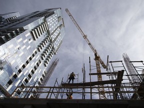 A construction worker erects scaffolding on a condominium building under construction in downtown Montreal.