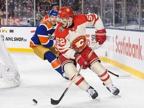 MacKenzie Weegar of the Calgary Flames carries the puck against Connor McDavid of the Edmonton Oilers.