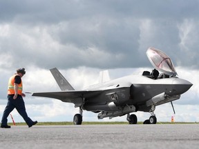 An Ottawa airport ground crew member walks past a F-35A Lightning II fighter jet in 2019.