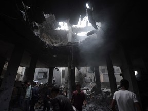 Palestinians look for survivors inside the remains of a destroyed building following an Israeli airstrike in Khan Younis refugee camp, southern Gaza Strip, Saturday, Nov. 18, 2023.