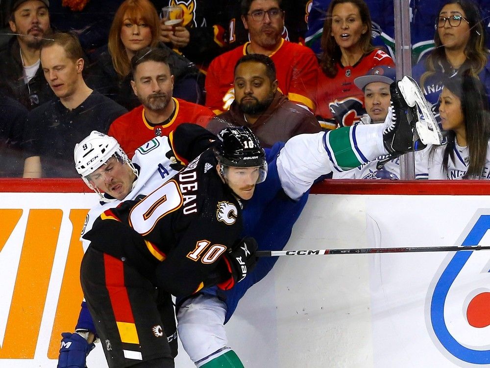 Calgary Flames forward Jonathan Huberdeau battles Vancouver Canucks forward J.T. Miller at the Scotiabank Saddledome in Calgary on Thursday, Nov. 16, 2023.