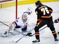 New York Islanders goalie Ilya Sorokin, left, tries to stop Calgary Flames forward Martin Pospisil from scoring during first period NHL hockey action in Calgary, Alta., Saturday, Nov. 18, 2023.