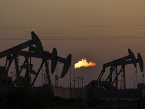 Flare burning off methane as oil pumpjacks operate