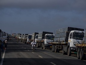 FILE - Trucks carry aluminum alloy frames to Adani Green Energy Limited's Renewable Energy Park near Khavda, Bhuj district near the India-Pakistan border in the western state of Gujarat, India, Sept. 21, 2023.