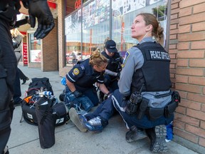 Members of the community safety team help a drug poisoning victim in Chinatown on June 22, 2023, in Edmonton.