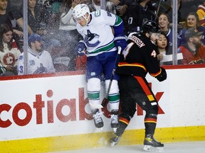 Calgary Flames defenceman Rasmus Andersson checks Vancouver Canucks forward Sam Lafferty at the Scotiabank Saddledome in Calgary on Saturday, Dec. 2, 2023.