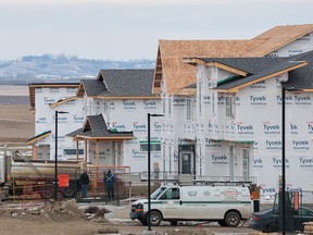 Construction workers build homes in the Livingstone development on the northern edge of Calgary on Tuesday, December 19, 2023.
