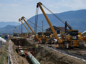 The company building the Trans Mountain pipeline expansion is warning the project's completion could be delayed by two years if the Canada Energy Regulator does not allow a previously rejected request for a pipeline variance. Workers lay pipe during construction of the Trans Mountain pipeline expansion on farmland, in Abbotsford, B.C., on Wednesday, May 3, 2023.