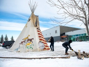 Firekeepers Tommy Standing, right, and Bryon Standing, both from Wahpeton Dakota Nation, cut and haul wood for the tipi during the public coroner's inquest into the mass stabbings that happened on James Smith Cree Nation in 2022 in Melfort, Sask., Tuesday, Jan. 16, 2024.