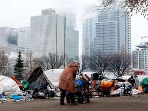 A resident hauls away their belongings as police and City of Edmonton crews remove a homeless encampment along 105A Avenue near 96 Street west of the Bissell Centre in Edmonton on Wednesday, Jan. 3, 2024.