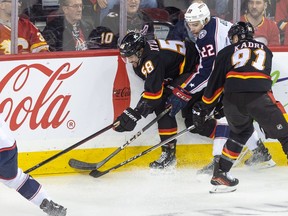 Calgary Flames defenceman Oliver Kylington holds possession while getting railroaded along the boards by Columbus Blue Jackets defenceman Jake Bean in the first period at the Saddledome on Thursday