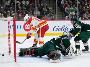Calgary Flames center Jonathan Huberdeau (10) scores a goal past Minnesota Wild goaltender Marc-Andre Fleury, center, and center Connor Dewar (26) during the first period of an NHL hockey game