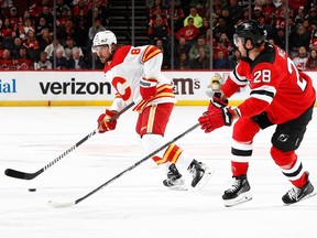 Chris Tanev #8 of the Calgary Flames controls the puck as Timo Meier #28 of the New Jersey Devils defends during the first period at Prudential Center