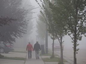 Pedestrians make their way through the heavy fog and smoke, in Edmonton Friday Aug. 25, 2023. A special air quality statement was issued as smoke from wildfires continues to cause poor air quality and reduced visibility. Photo by David Bloom