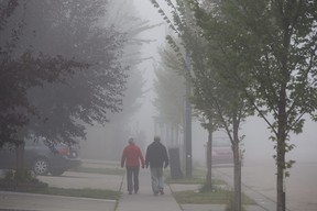 Pedestrians make their way through the heavy fog and smoke, in Edmonton Friday Aug. 25, 2023. A special air quality statement was issued as smoke from wildfires continues to cause poor air quality and reduced visibility. Photo by David Bloom