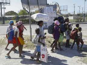 People flee their homes due to gang violence as they walk to a police station in Port-au-Prince, Haiti, Monday, Feb. 12, 2024.