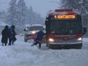 File photo: Commuters step through snow ruts to get on a bus after a winter storm hit the city on Tuesday, December 22, 2020.