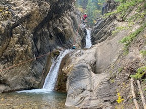 An image of a person descending a waterfall while canyoning near Abraham Lake near Nordegg, Alberta, Canada.