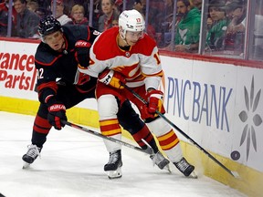 Calgary Flames' Yegor Sharangovich (17) protect the puck from Carolina Hurricanes' Evgeny Kuznetsov (92) during the first period of an NHL hockey game in Raleigh, N.C