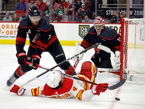 Carolina Hurricanes' Jaccob Slavin (74) takes Calgary Flames' Rasmus Andersson (4) off the puck in front of Hurricanes goaltender Frederik Andersen (31) during the third period of an NHL hockey game in Raleigh, N.C