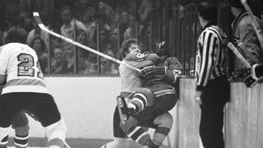 Philadelphia Flyers center Bobby Clarke (16) pushes Montreal Canadiens defenseman Bob Murdoch (23) into the boards in the third period of an NHL semifinal playoff game, April 22, 1973 in Philadelphia. Murdoch's family says the two-time Stanley Cup champion suffered from chronic traumatic encephalopathy, a progressive and fatal disease associated with repeated traumatic brain injuries.