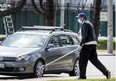 A man pictured during the pandemic on April 16, 2020, uses a pole with a cup on the end to ask for change from drivers on Toronto’s Lakeshore Blvd. (Postmedia News photo)